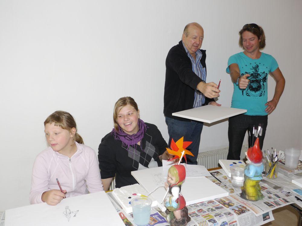 Zwei Betreuerinnen mit zwei Kindern beim gemeinsamen Basteln an einem Tisch.